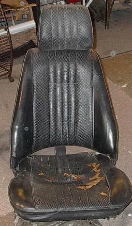 A before picture of a black leather bucket seat prior to upholstery and foam repairs.